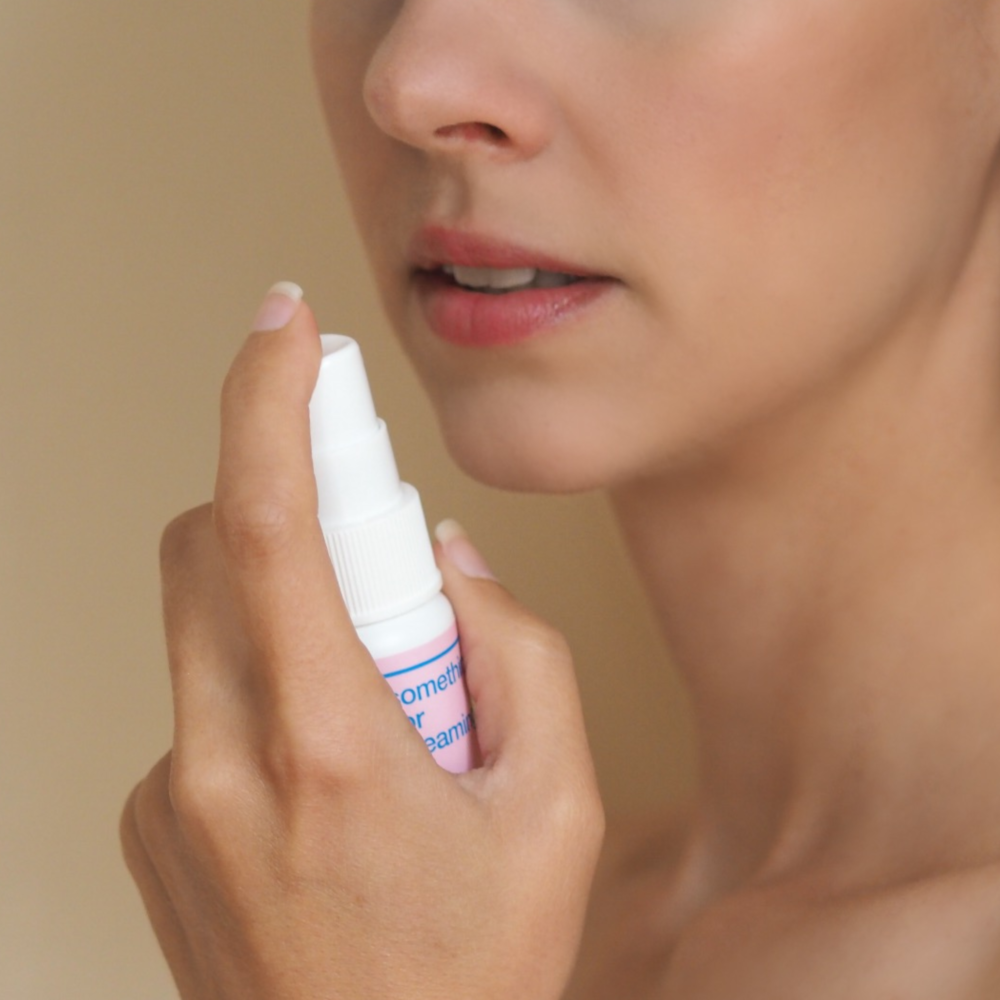 woman holding sleep spray up to her mouth