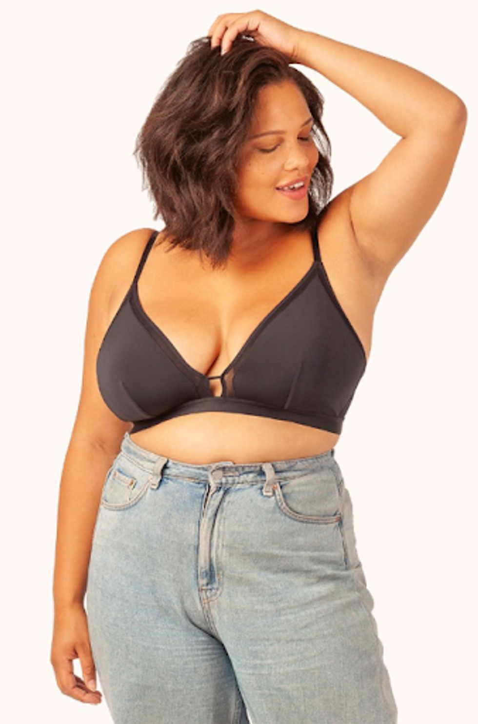 A tan girl smiles in a Lively black "Busty Bralette" and jeans